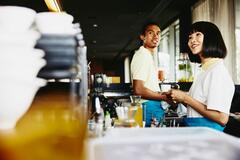 two baristas making coffee and smiling