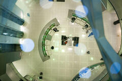 Top view of modern futuristic office hall with semicircular rows of armchairs and elevators aside.