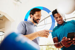 Two smiling colleagues (men) looking at a phone.