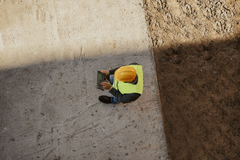Arial view of a construction worker on tablet device outdoors.