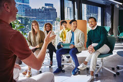 Group of people having a meeting, in a room with glass windows.