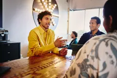 3 persons having a meeting and sitting at a table