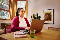 Female working on laptop on a table at home
