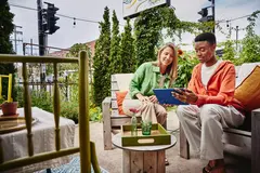 Female and male sitting on terras looking at a tablet