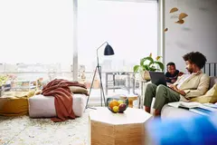 male sitting on couch with his laptop, looking serious at a kid 
