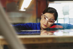 Womale wearing safety glasses and gloves watching a process closely.
