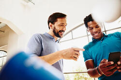 Two smiling colleagues (men) looking at a phone.
