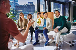 Group of people having a meeting, in a room with glass windows.