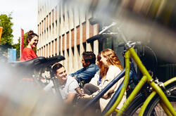 Group of students sitting outside next to bikes.