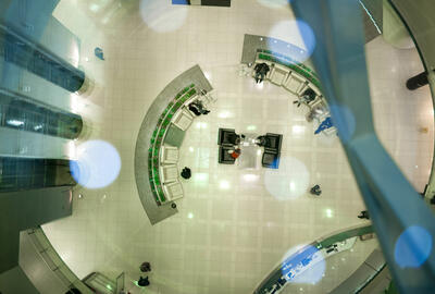 Top view of modern futuristic office hall with semicircular rows of armchairs and elevators aside.