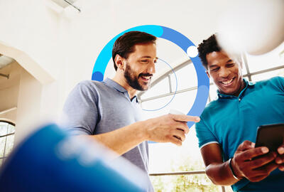 Two smiling colleagues (men) looking at a phone.