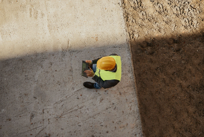 Arial view of a construction worker on tablet device outdoors.