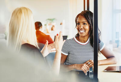Two women smiling, having a conversation