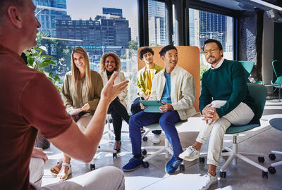 Group of people having a meeting, in a room with glass windows.