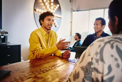 3 persons having a meeting and sitting at a table