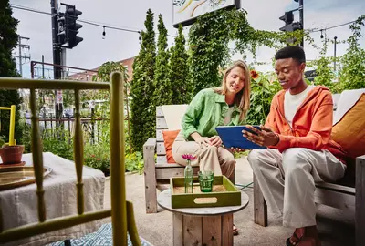 Female and male sitting on terras looking at a tablet