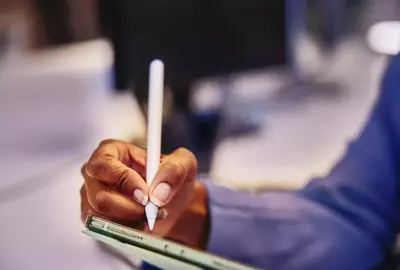 Close up of a hand holding a touch pen and a tablet