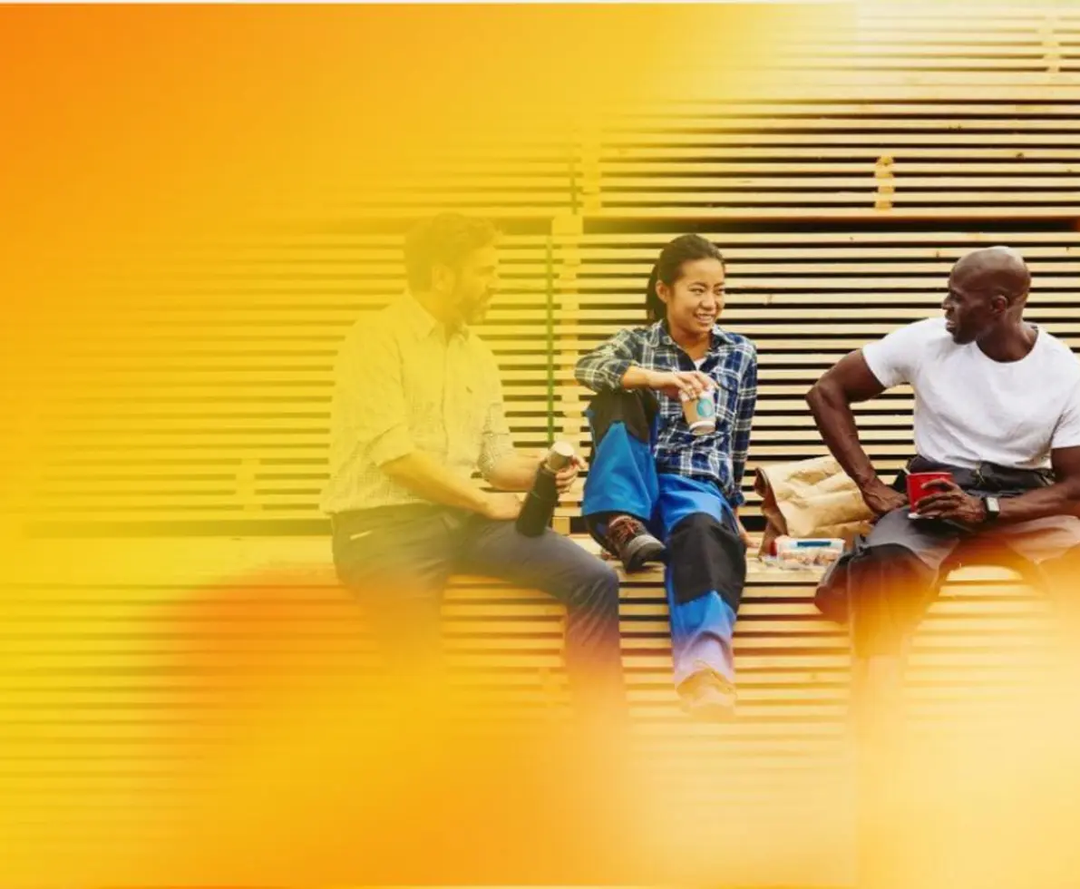 Two male and one female person sitting and chatting in a manufacturing environment