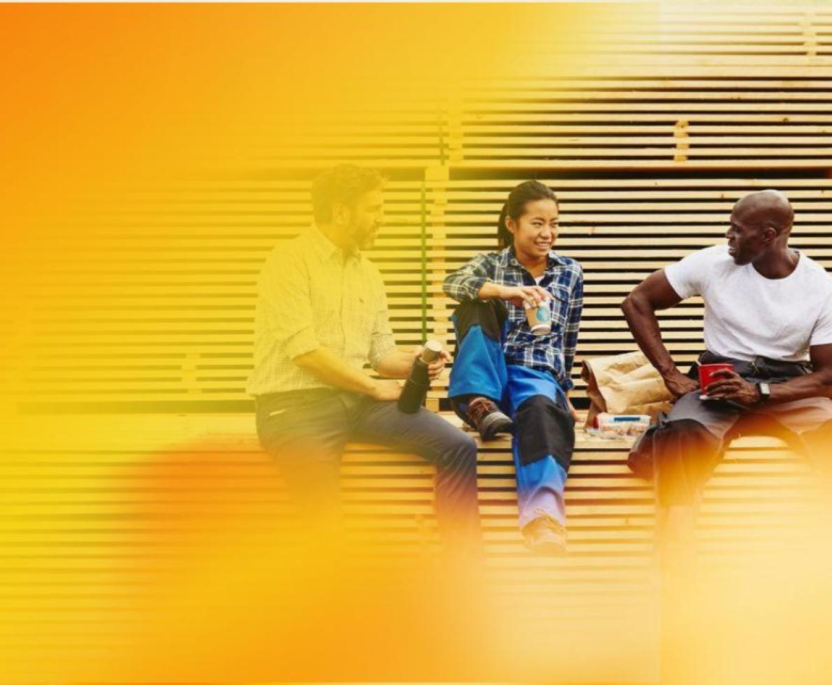 Two male and one female person sitting and chatting in a manufacturing environment