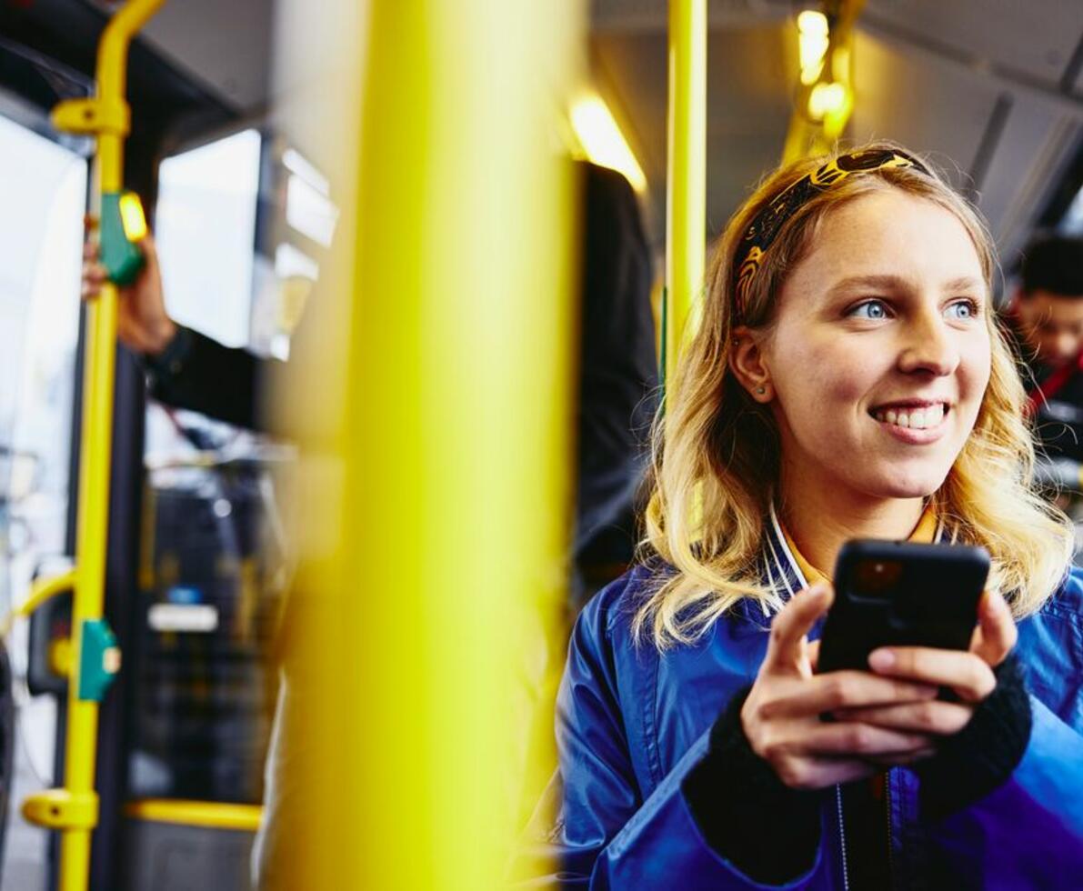 woman smiling on the bus using her phone