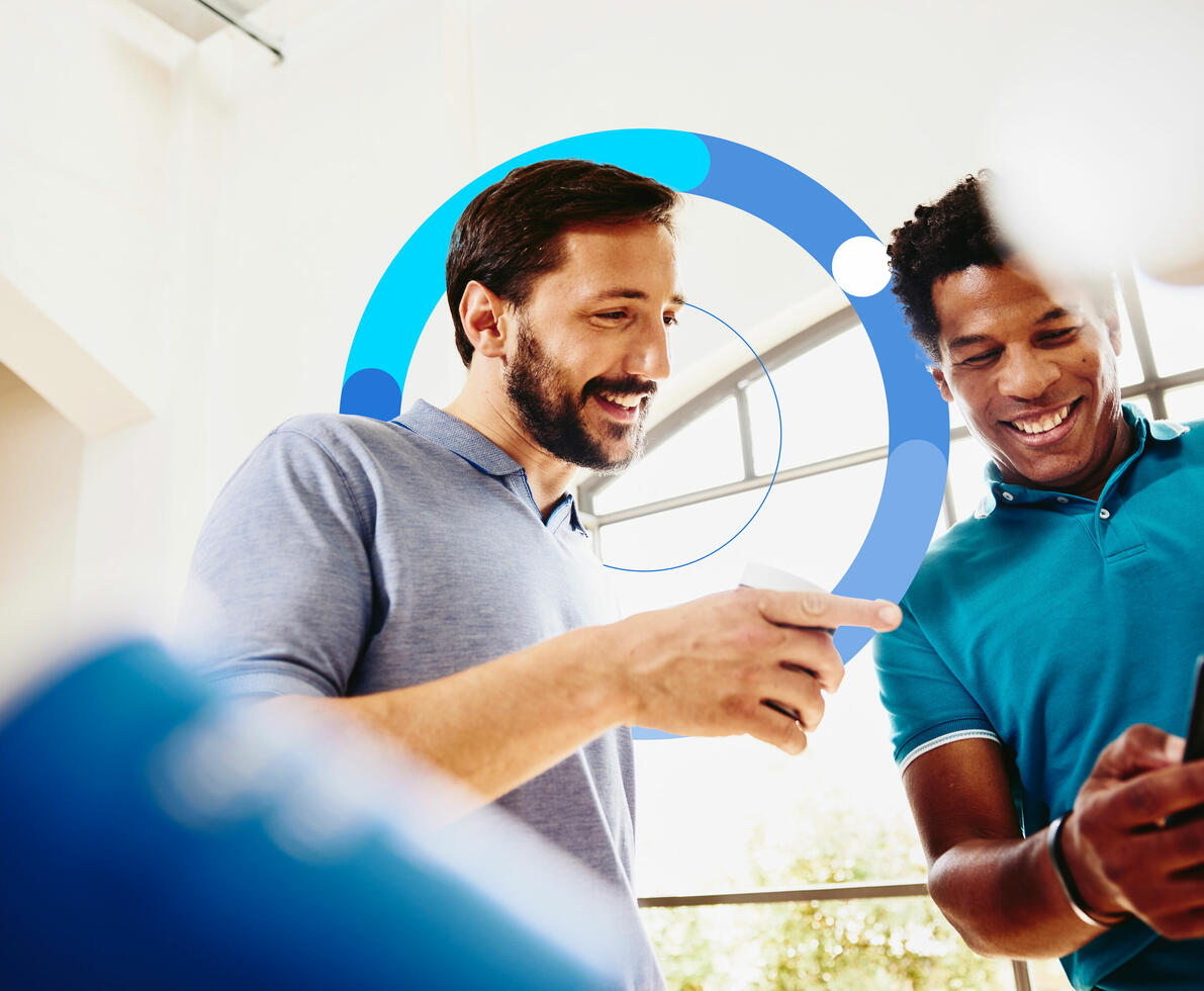Two smiling colleagues (men) looking at a phone.