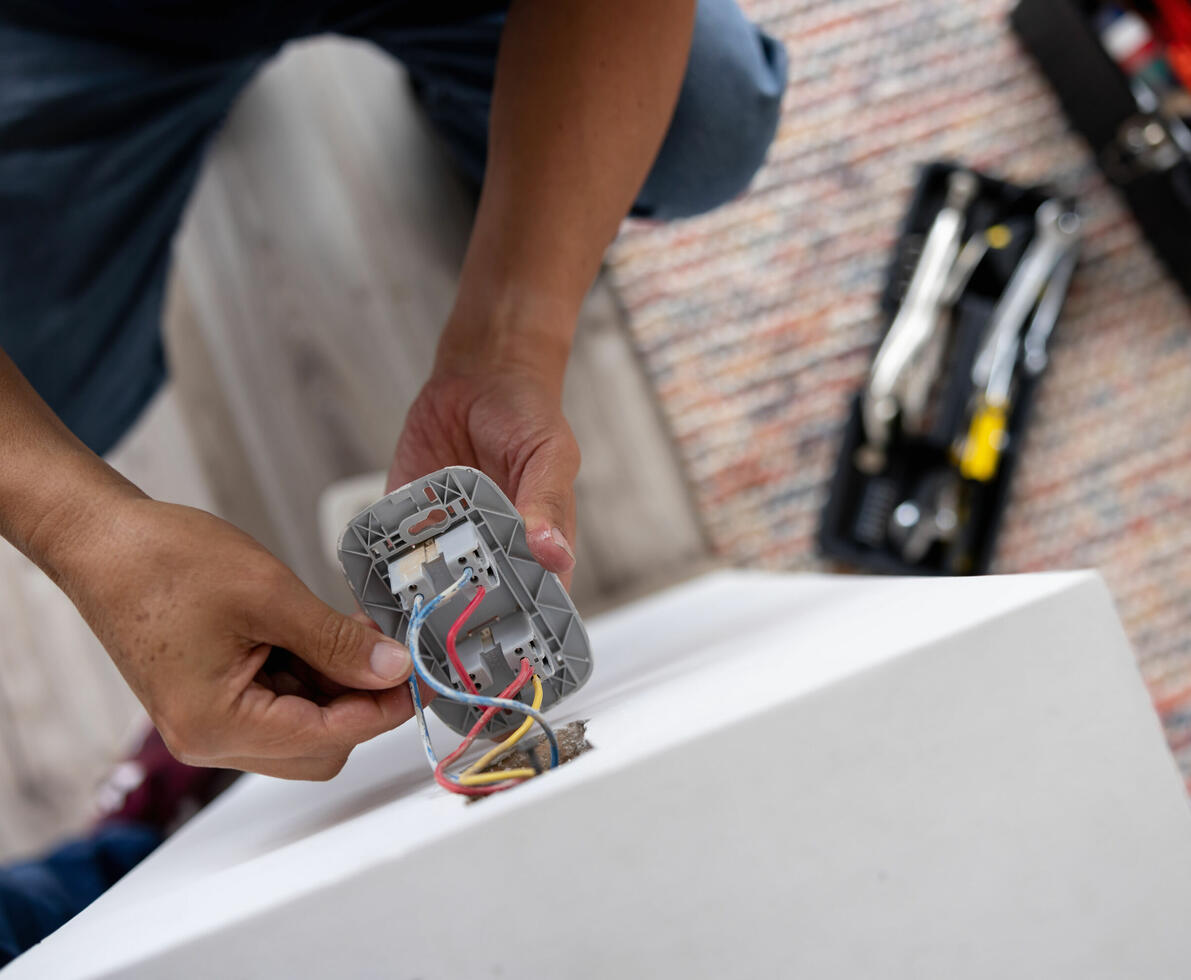 Close-up on a repairman fixing an electrical outlet - electricity concepts
