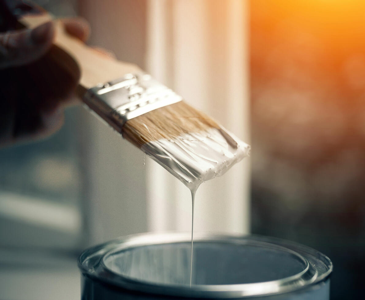 A can of paint and a brush in white paint.