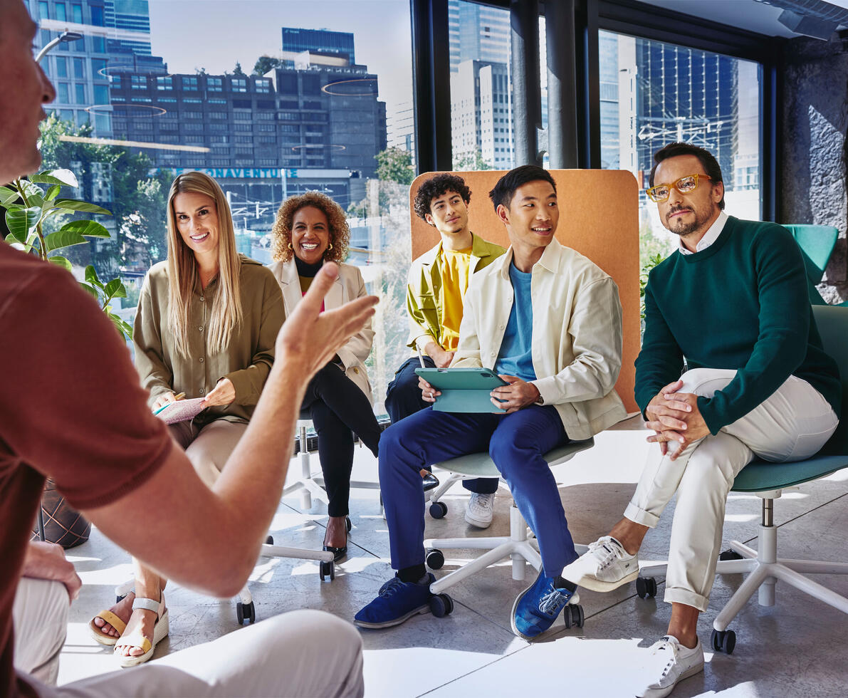 Group of people having a meeting, in a room with glass windows.