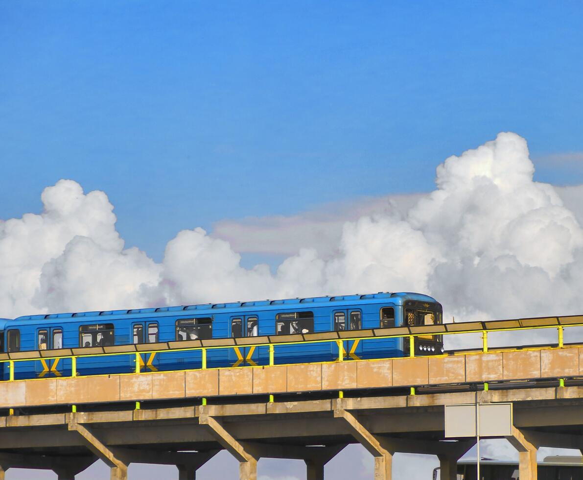 Blue metro train on a bridge with blue sky in the background