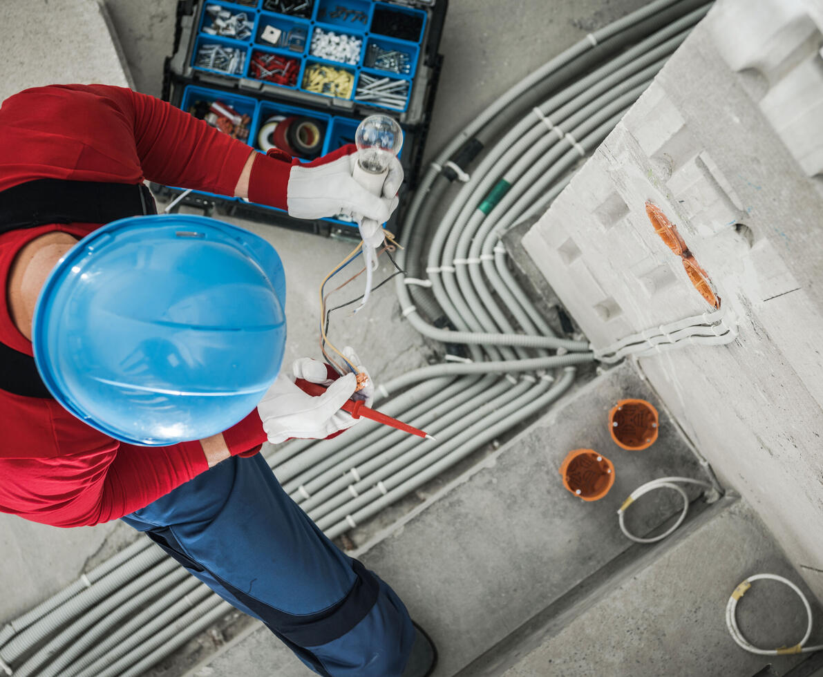 Top view of electrician checking wires while performing electrical wiring installation.