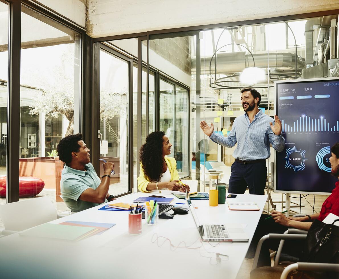 Four colleagues having a meeting in a meeting room. Financial charts in the background. Four colleagues having a meeting in a meeting room. Financial charts in the background.