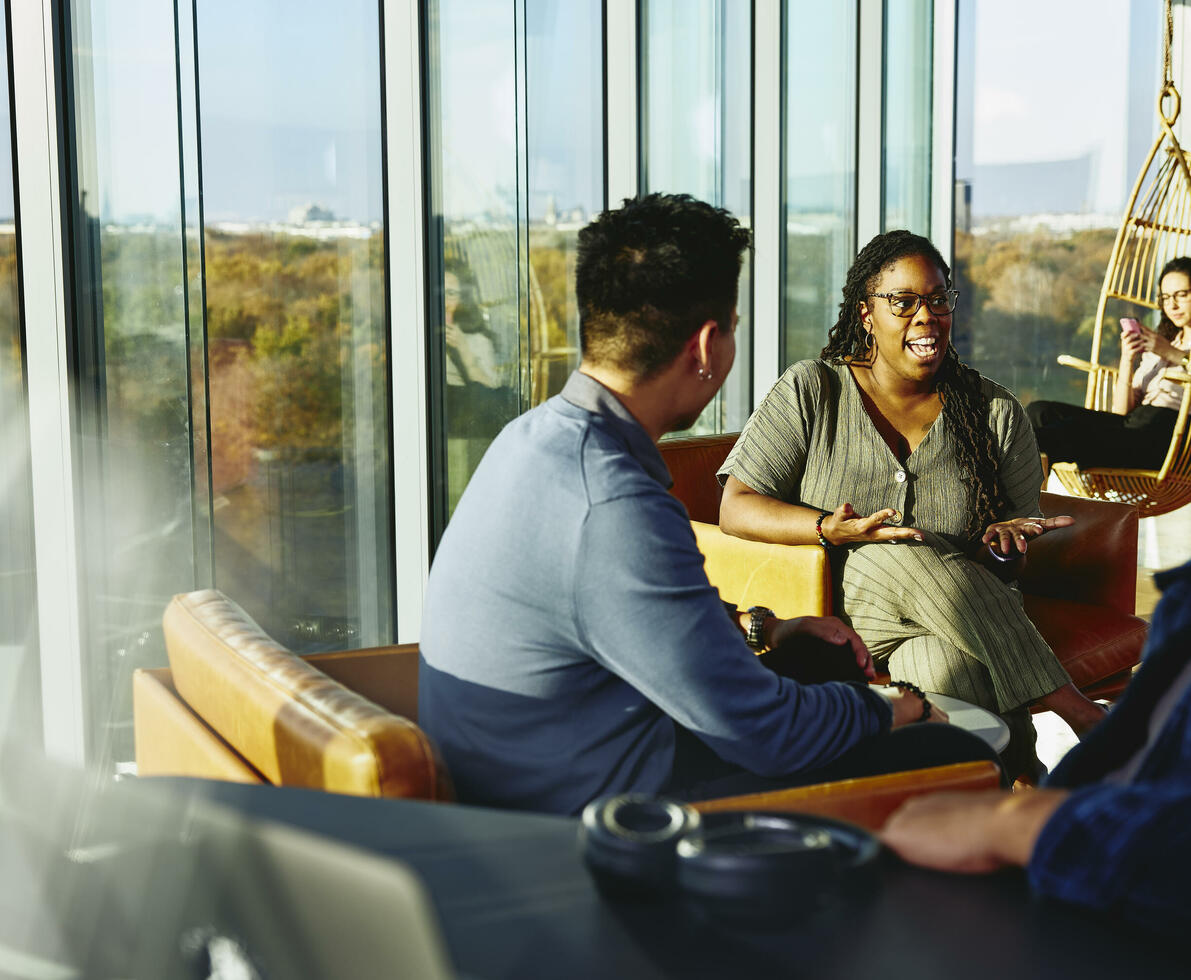 Two people having a conversation while sitting down in a lounge environment.
