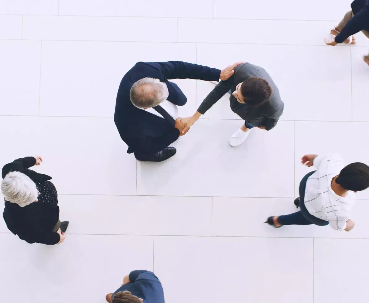 Aerial view of two people shaking hands while people walk by.