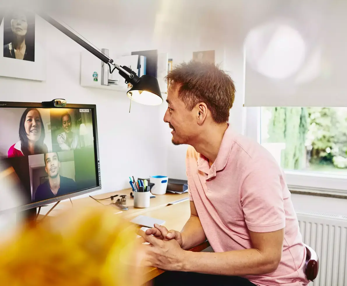 male sitting at desk in his home office, meeting colleagues in a online meeting.
