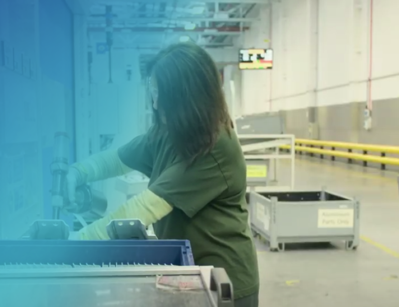 Woman using a drill in a factory