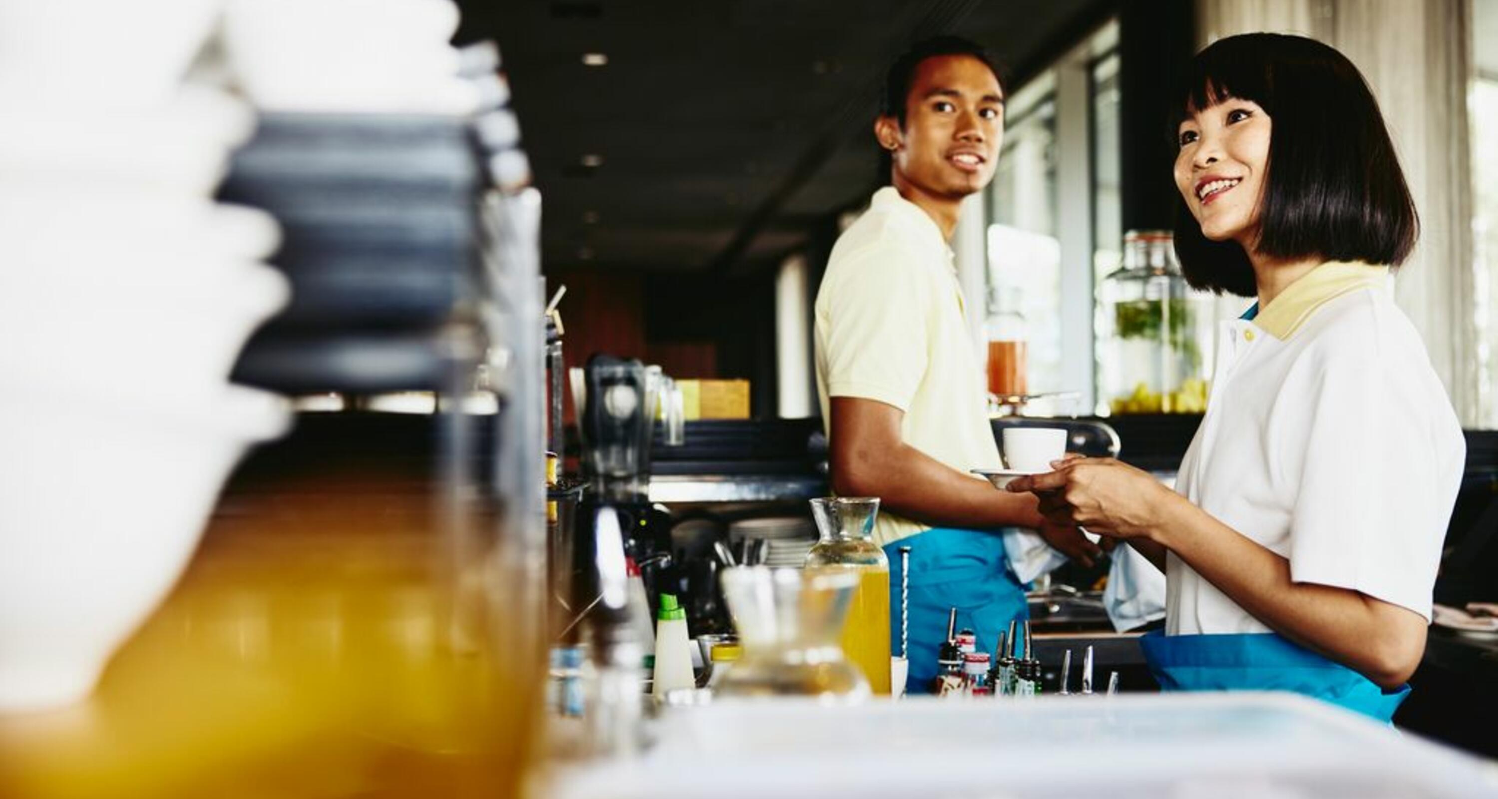 two baristas making coffee and smiling
