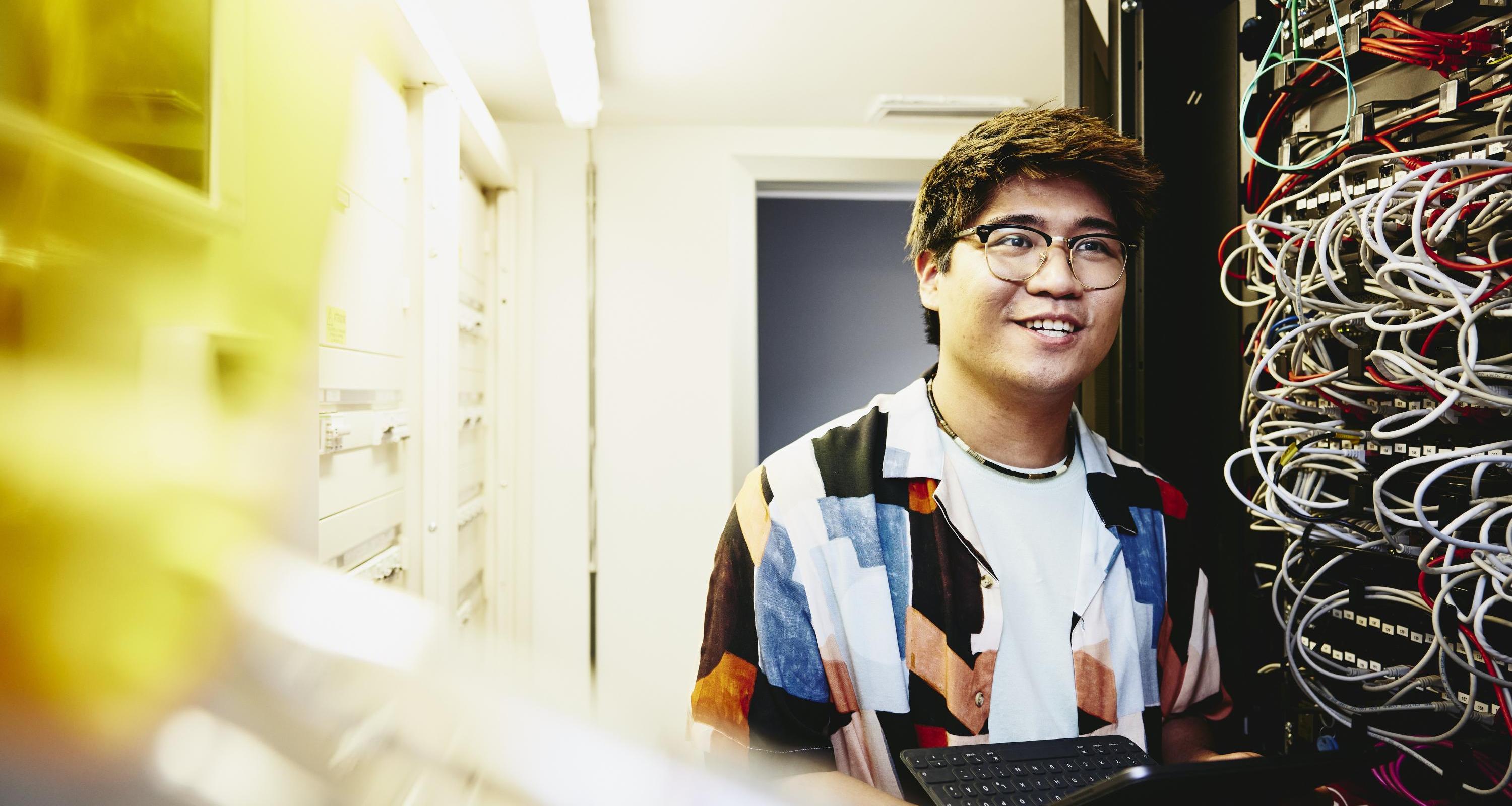 Smiling man holding an tablet standing in a servers room.