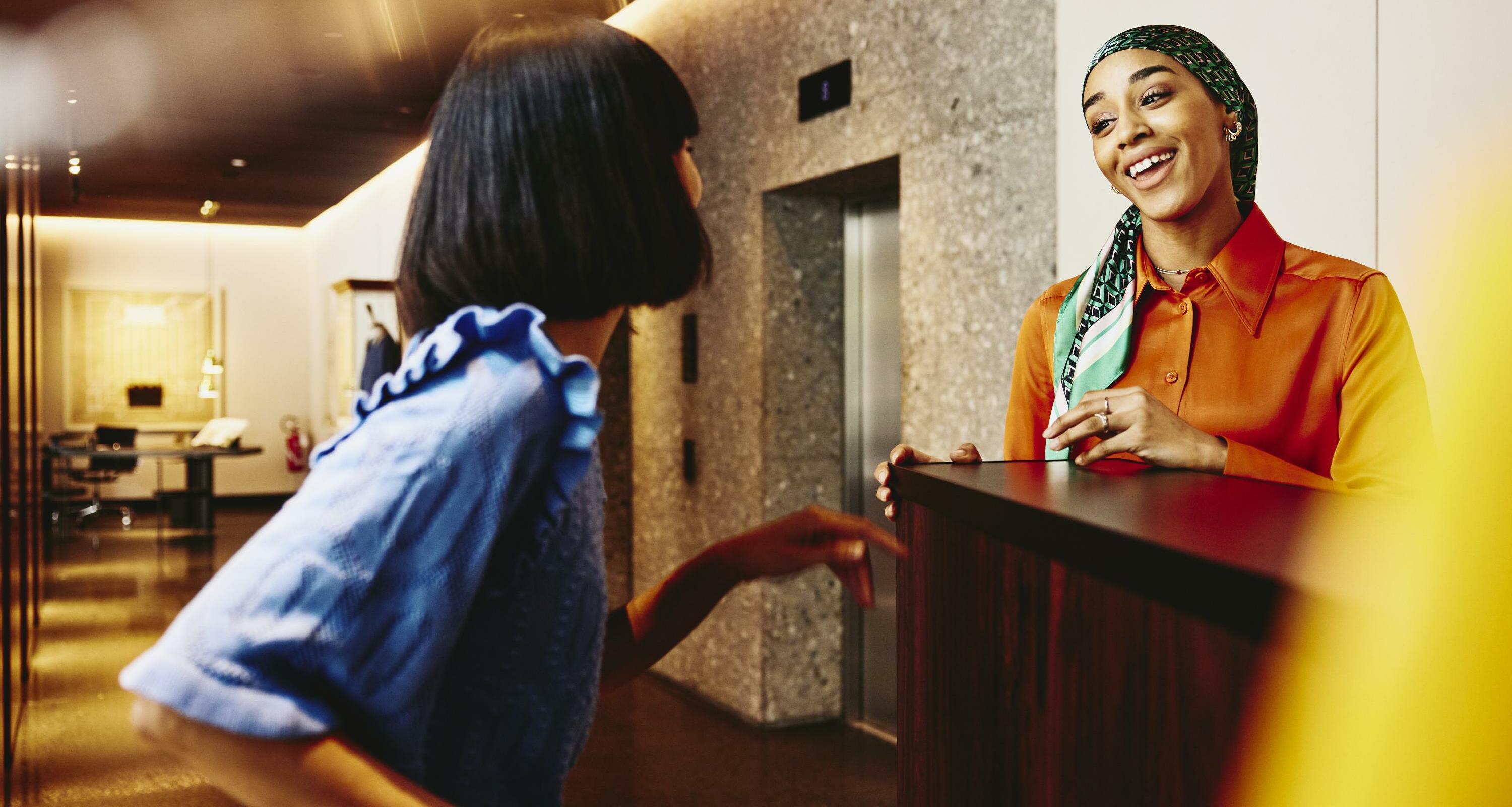 Smiling hotel receptionist helping a guest. 