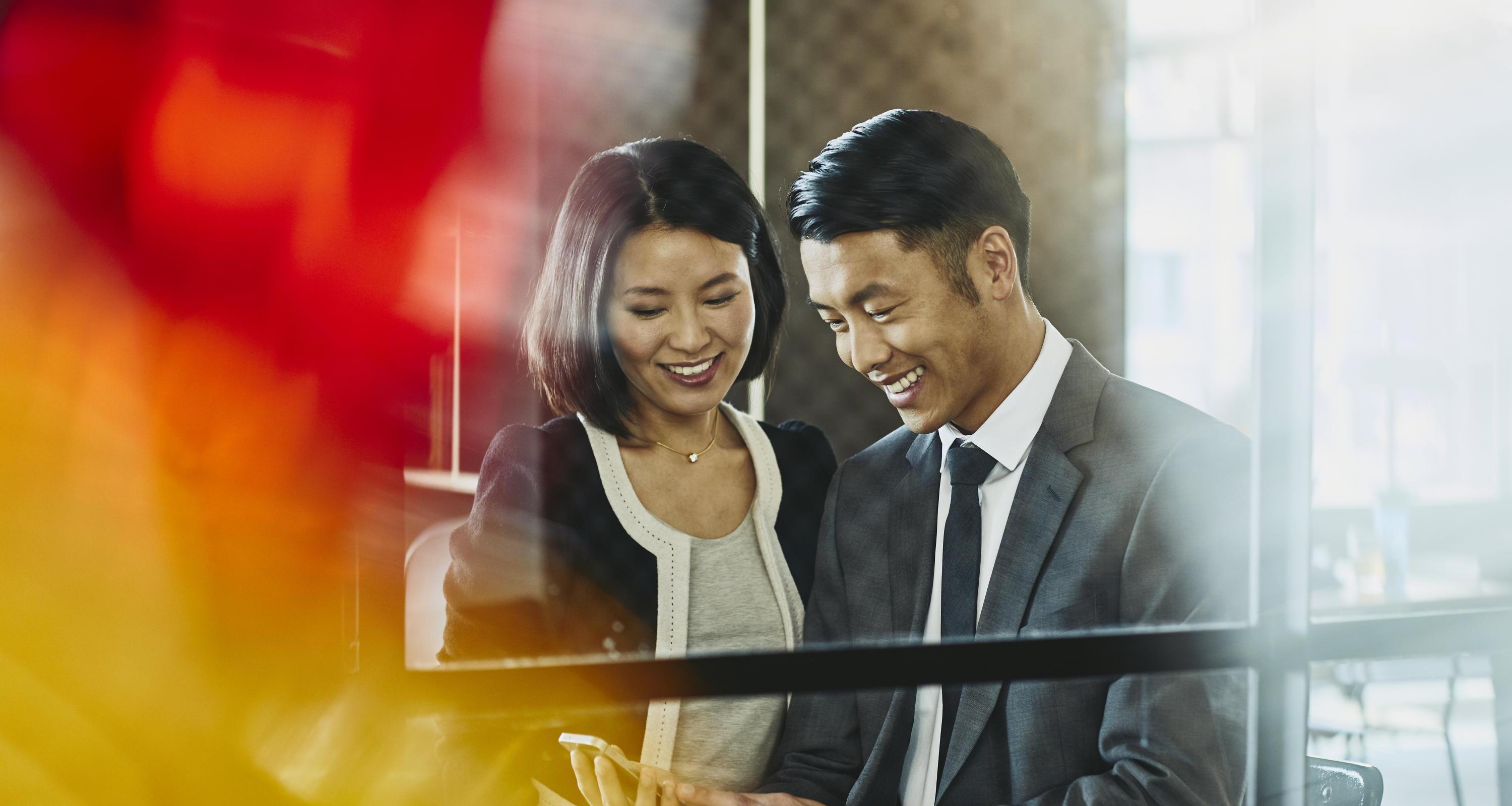 Man and woman looking at chell phone. China. Primary colors: red and yellow.