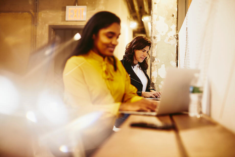 Two women working on their laptops