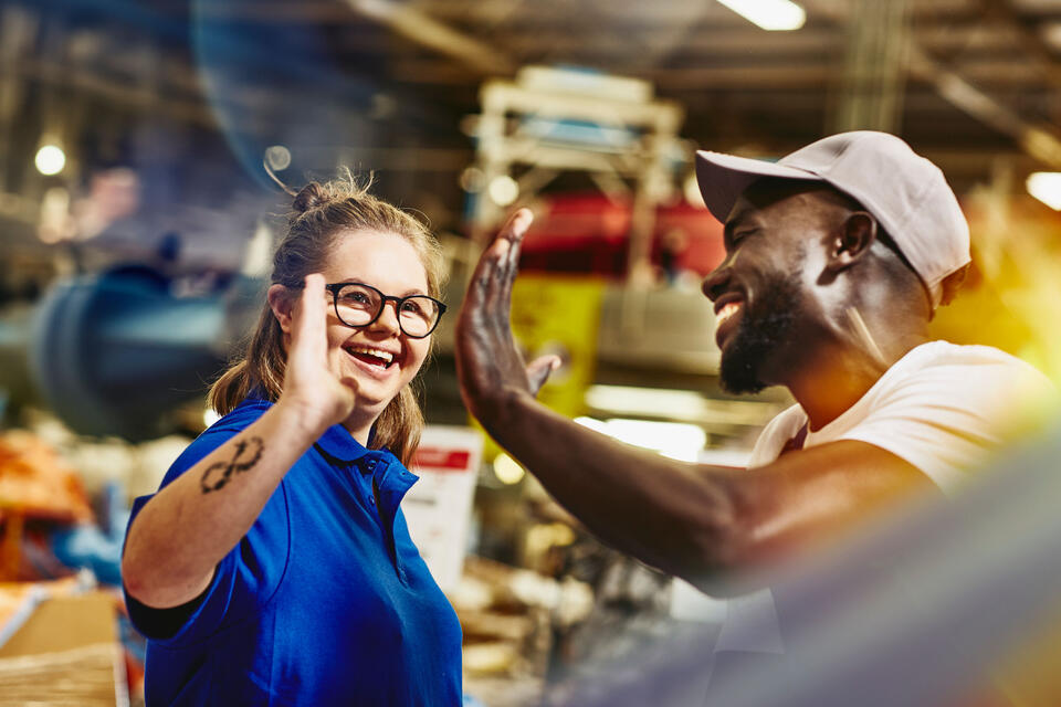 Man and woman giving each other a high five in a warehouse.