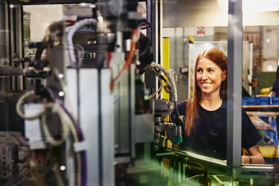 A woman working with automated machinery in a factory setting.